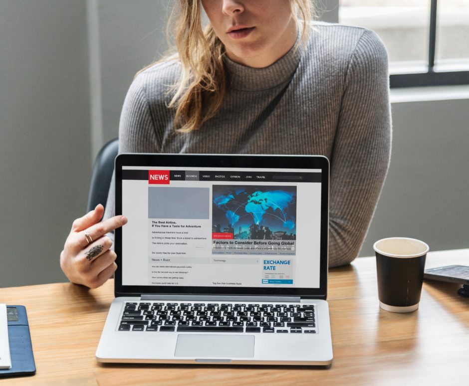 woman points to laptop screen showing news site