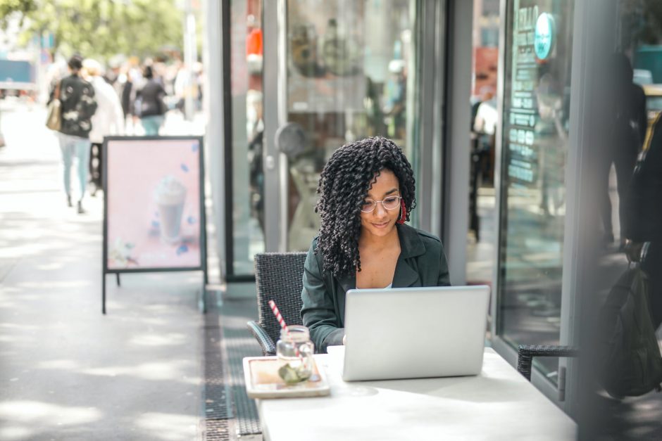 woman working on a laptop outdoors at a coffee shop