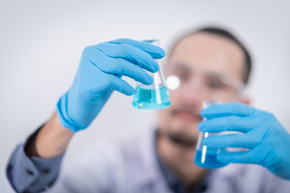 a scientist holds up two beakers of liquid